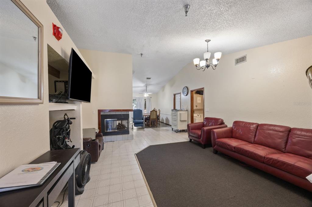A living room with a red leather sofa, fireplace, and tile and carpet flooring — 2700 STATE ROAD 590, CLEARWATER, FL