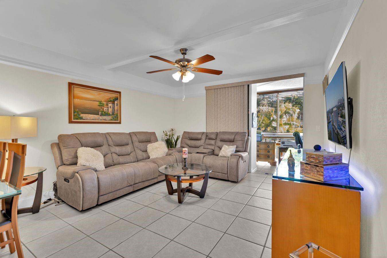 A living room features a beige sectional sofa, glass coffee table, tile flooring, and a ceiling fan — 6850 Royal Palm Boulevard # 106, Margate FL 33063, MARGATE, FL