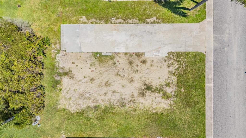 An aerial view shows a vacant residential lot with a concrete driveway and sandy ground — 605 MICHIGAN BOULEVARD UNIT 105, DUNEDIN, FL