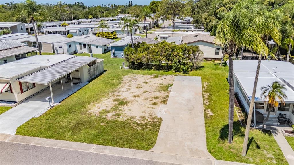 An aerial view shows a vacant lot with a concrete driveway between two mobile homes — 605 MICHIGAN BOULEVARD UNIT 105, DUNEDIN, FL