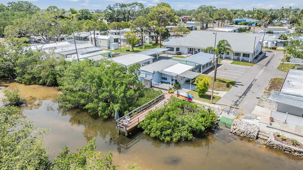 An aerial view shows a waterfront mobile home with a private dock and nearby clubhouse — 605 MICHIGAN BOULEVARD UNIT 105, DUNEDIN, FL