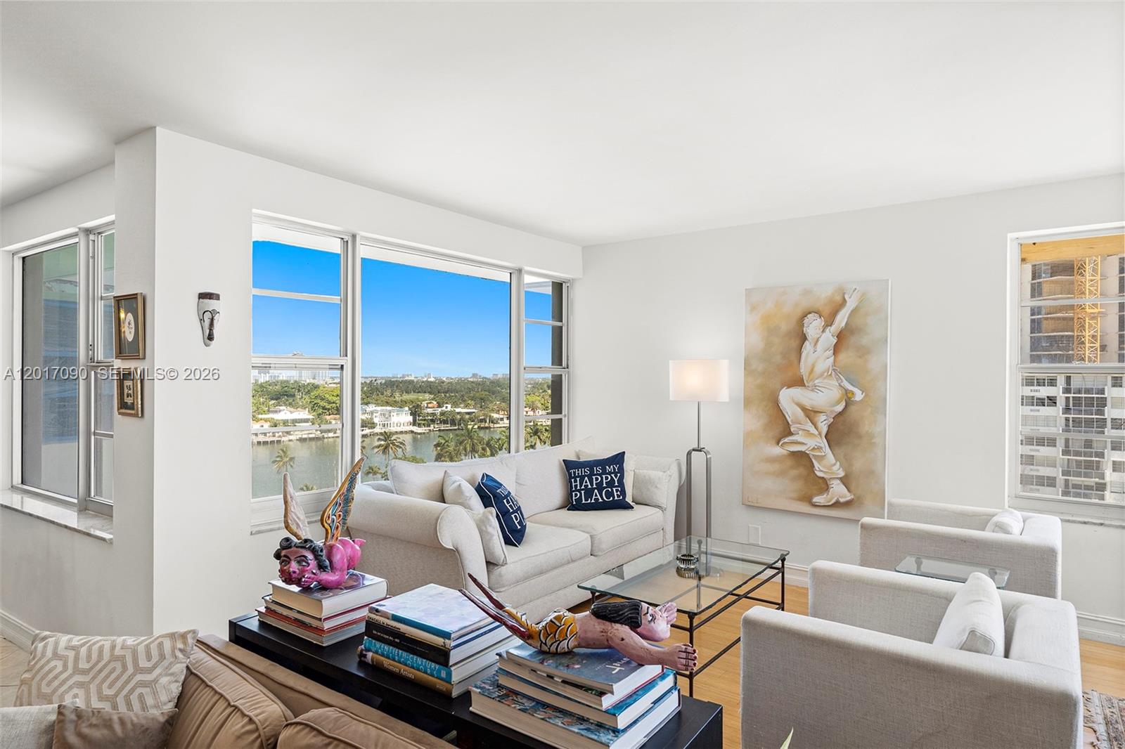 A bright living room features a white sofa, armchairs, glass coffee table, and waterfront views — 5255 Collins Ave # 9F, Miami Beach FL 33140, MIAMI BEACH, FL