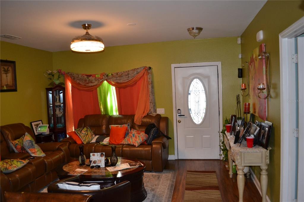 A living room features brown leather sofas, a round coffee table, and a white front door — 509 MARICOPA DRIVE, KISSIMMEE, FL