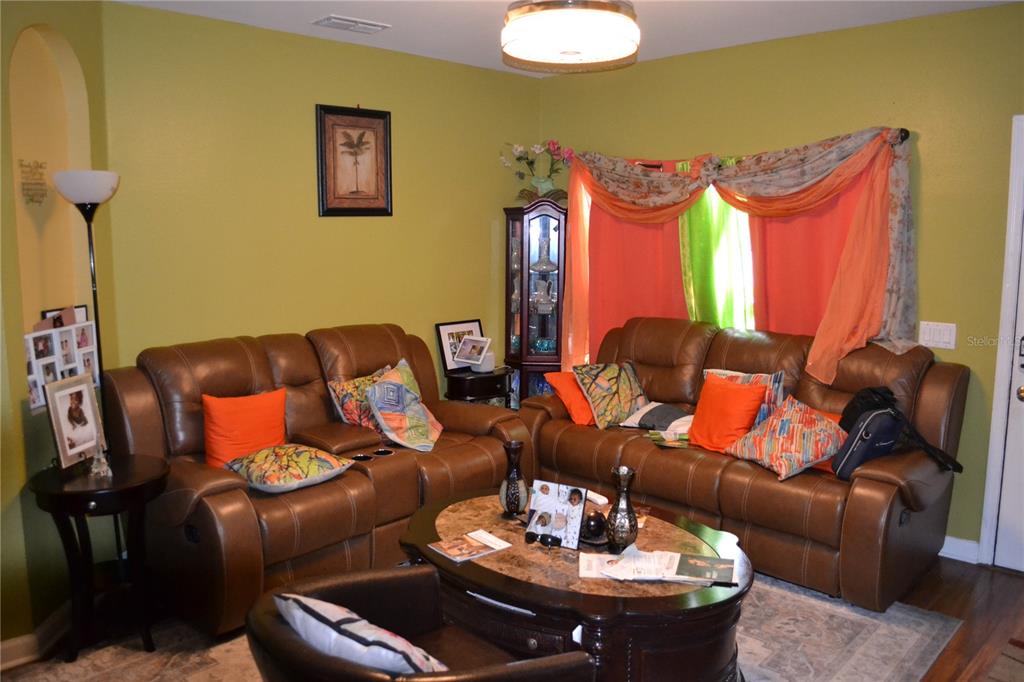 A living room features two brown leather sofas, a coffee table, and lime green walls — 509 MARICOPA DRIVE, KISSIMMEE, FL