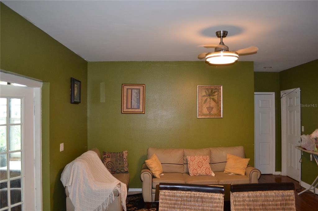 A living room with olive green walls, a beige sofa, and a ceiling fan — 509 MARICOPA DRIVE, KISSIMMEE, FL