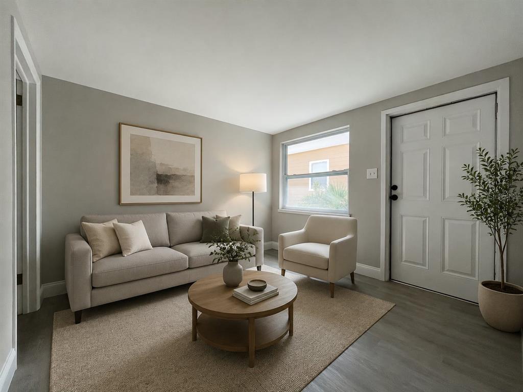 A living room features a beige sofa, armchair, round wooden coffee table, and gray flooring — 2704 E COLUMBUS DRIVE UNIT A, TAMPA, FL