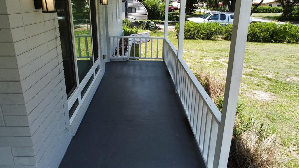 A covered porch features a dark painted concrete floor and white railings — 2462 HARVARD ROAD, DELAND, FL