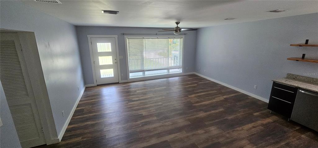 A living room features light blue walls, wood-look flooring, a ceiling fan, and a kitchenette area — 2462 HARVARD ROAD, DELAND, FL