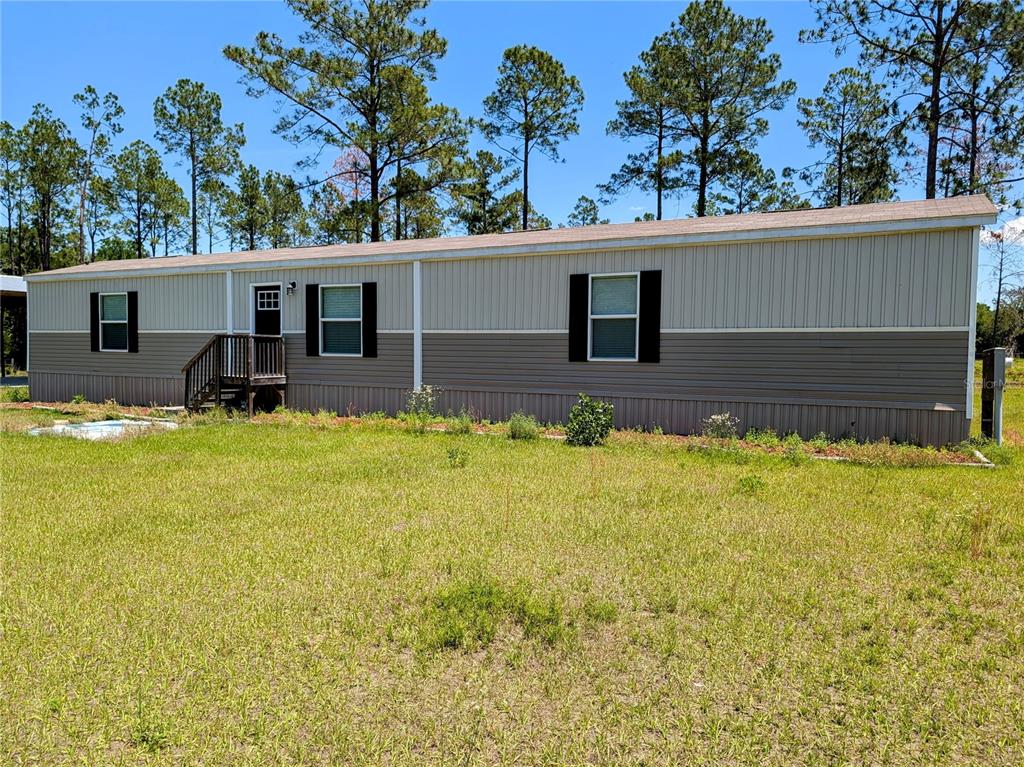 An aerial view shows a house and a detached metal carport on a grassy lot — 14421 NW 214TH TERRACE, HIGH SPRINGS, FL