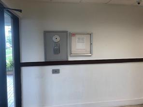 A white wall features a door, a wall-mounted keypad, and a framed notice board — 4174 Inverrary Drive # 907, Lauderhill FL 33319, LAUDERHILL, FL