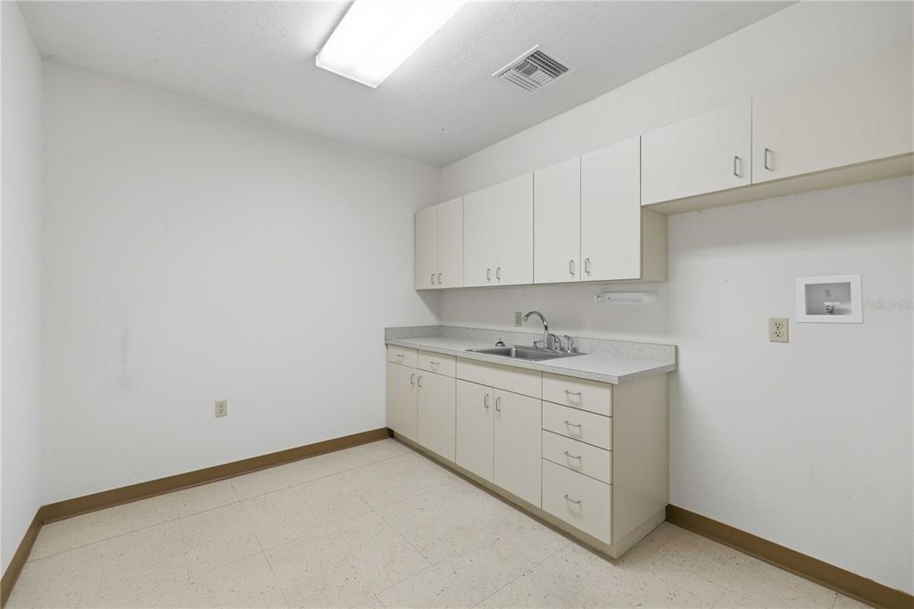 A laundry room features white cabinets, a stainless steel sink, and beige tile flooring — 4370 NE 35TH STREET UNIT 3, OCALA, FL