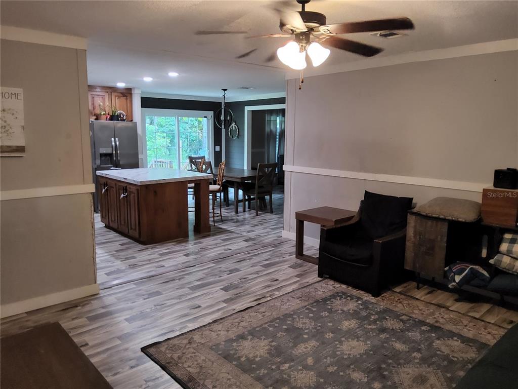 An open-concept living room and kitchen featuring wood-look flooring and a central island — 3200 SE 107TH PLACE, OCALA, FL