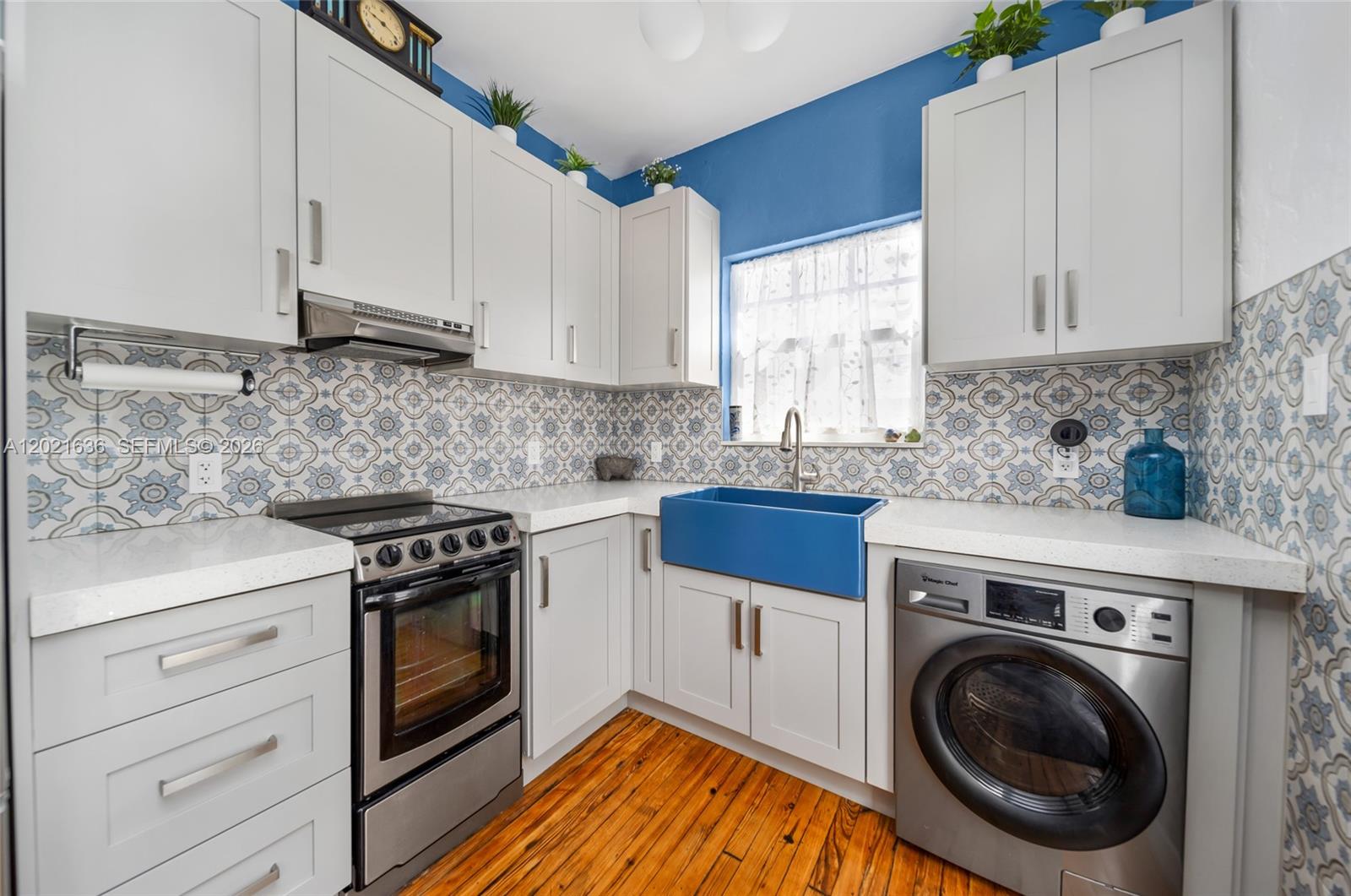 A kitchen features light gray cabinets, a blue farmhouse sink, and patterned backsplash tiles — 408 W 25th St # 8, Miami Beach FL 33140, MIAMI BEACH, FL
