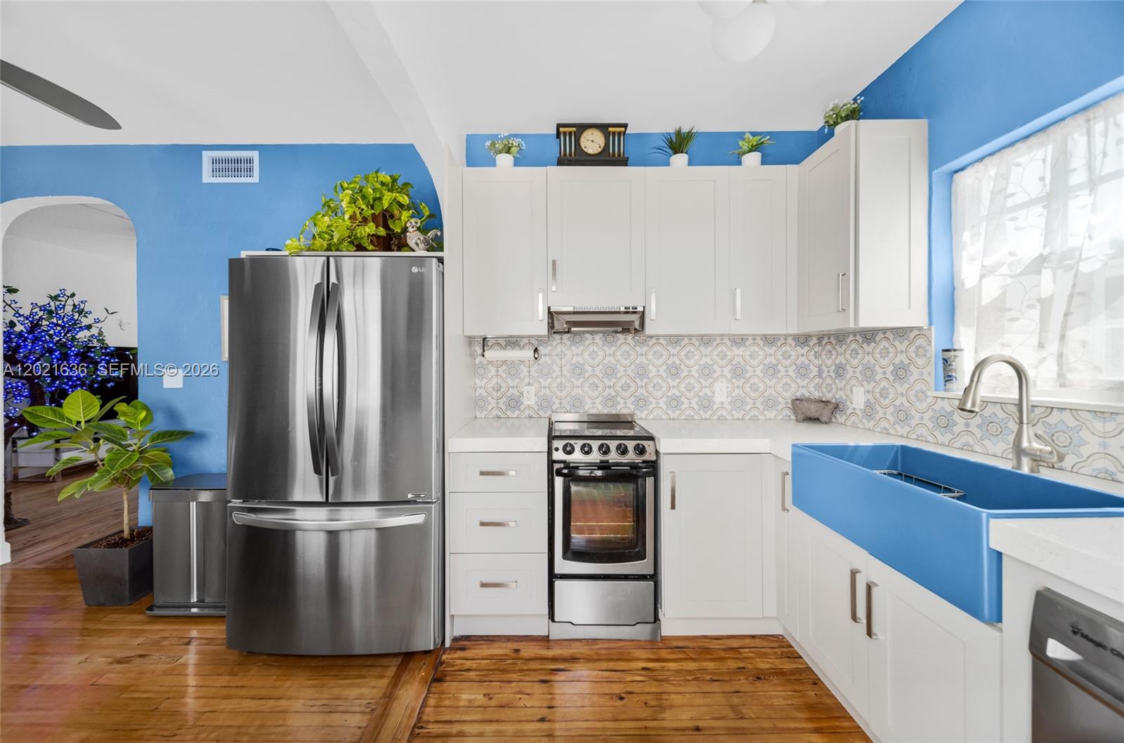 A kitchen features white cabinets, stainless steel appliances, a blue farmhouse sink, and blue walls — 408 W 25th St # 8, Miami Beach FL 33140, MIAMI BEACH, FL