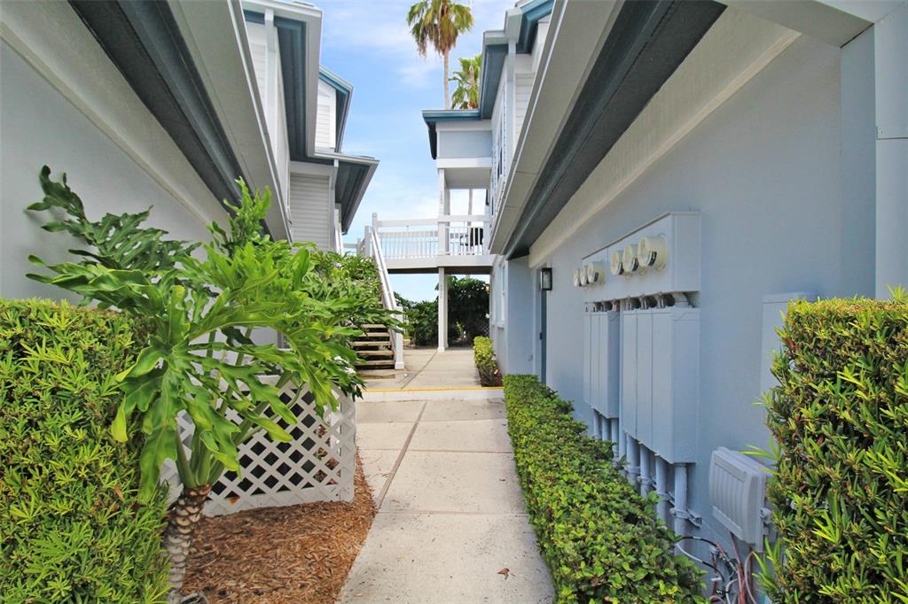 A concrete walkway leads between two light blue buildings with a bridge connecting them above — 1335 SIESTA BAYSIDE DRIVE UNIT 1335C, SARASOTA, FL