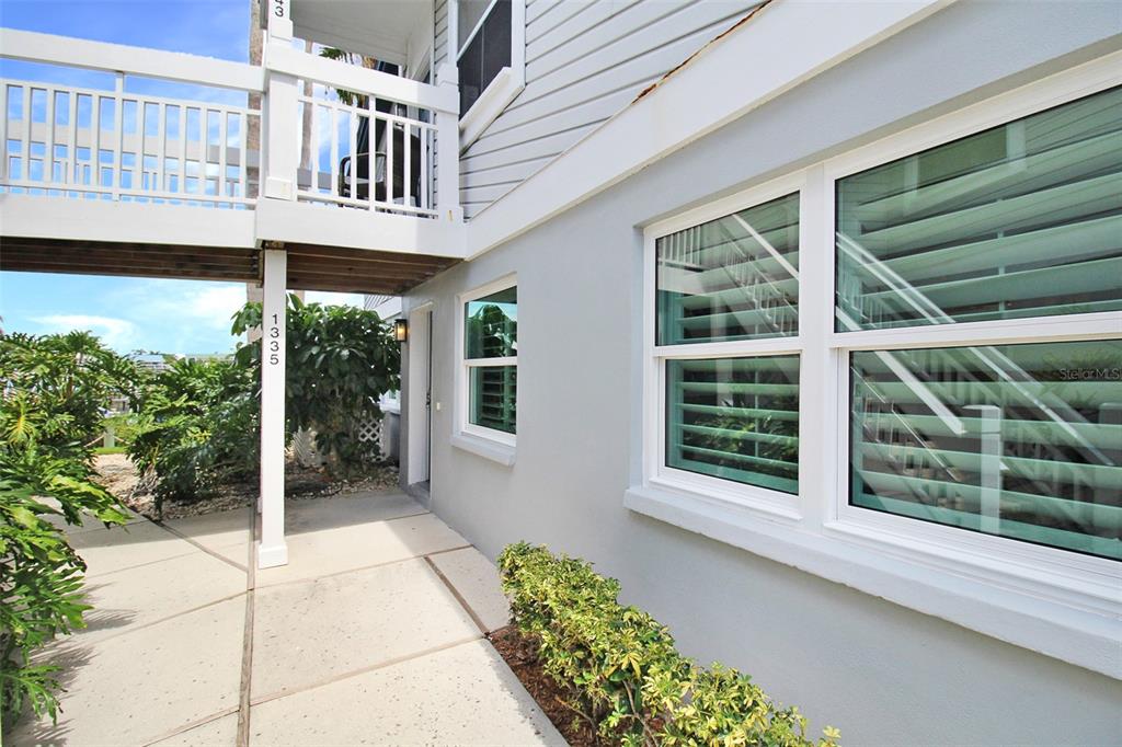 A ground-level view of a light gray house exterior with a white balcony and walkway — 1335 SIESTA BAYSIDE DRIVE UNIT 1335C, SARASOTA, FL