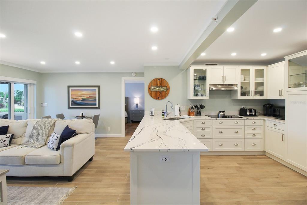 An open-concept kitchen with white cabinets and a marble island overlooks a living room area — 1335 SIESTA BAYSIDE DRIVE UNIT 1335C, SARASOTA, FL