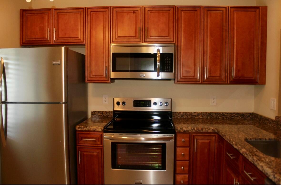 A kitchen features stainless steel appliances, wood cabinets, and granite countertops — 21943 Remsen Terrace # 204, Boca Raton FL 33433, BOCA RATON, FL