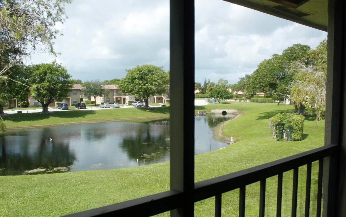 View from a balcony overlooking a grassy lawn, a small pond, and apartment buildings — 21943 Remsen Terrace # 204, Boca Raton FL 33433, BOCA RATON, FL