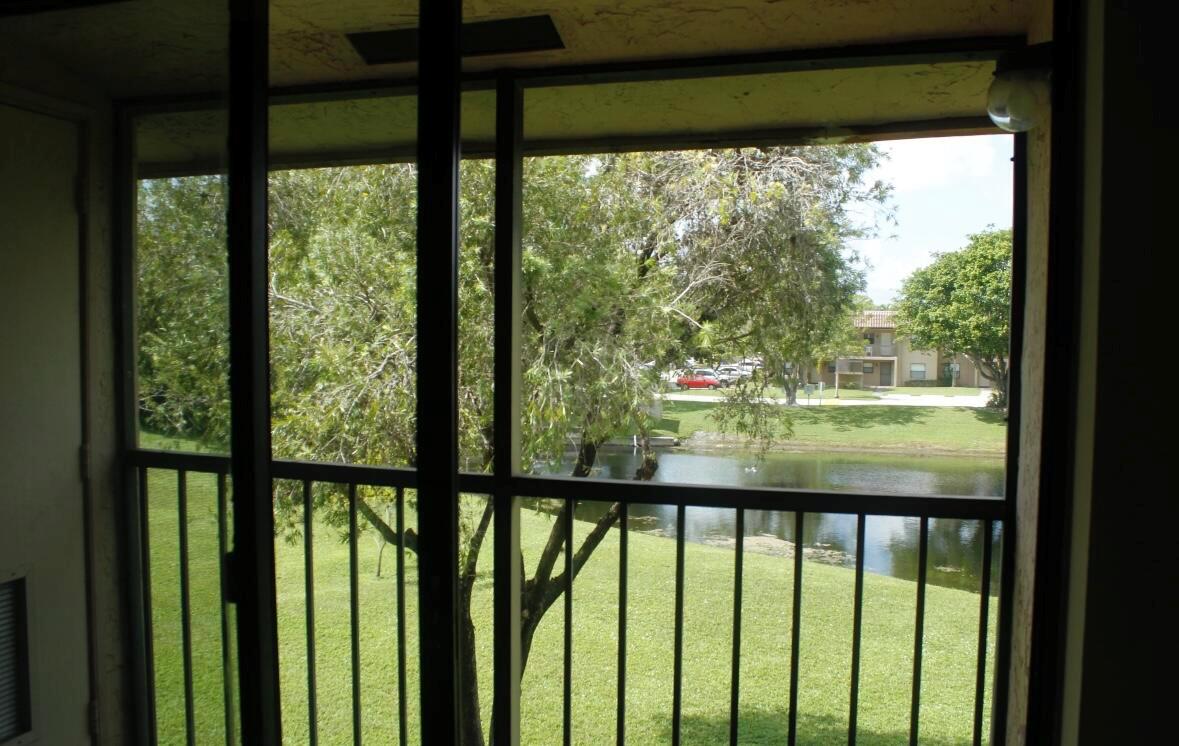 A view of a grassy lawn and a pond seen through a screened-in balcony — 21943 Remsen Terrace # 204, Boca Raton FL 33433, BOCA RATON, FL