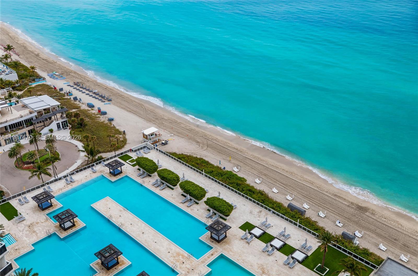 An aerial view shows a multi-level swimming pool deck adjacent to a sandy beach — 1830 S Ocean Dr # 2808, Hallandale Beach FL 33009, HALLANDALE BEACH, FL