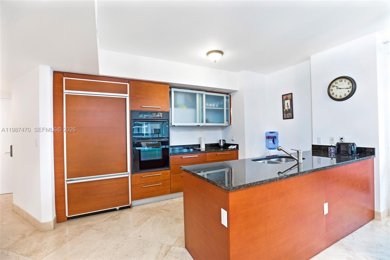 A kitchen features wood cabinetry, a black granite island, and stainless steel appliances — 1830 S Ocean Dr # 2808, Hallandale Beach FL 33009, HALLANDALE BEACH, FL