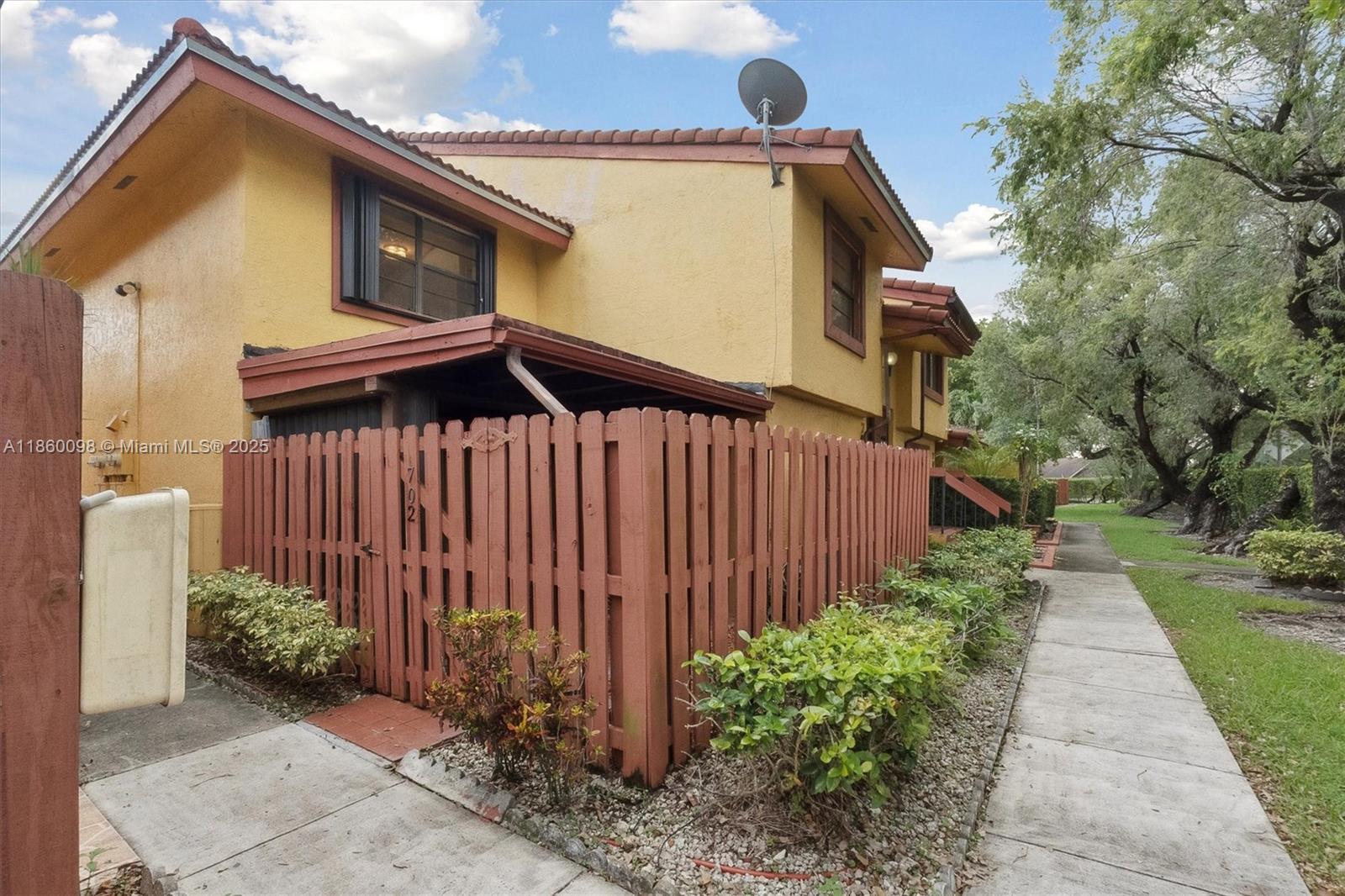A two-story yellow townhouse with a red-painted wooden fence and a tiled roof — 5975 SW 137th Ave # 702, Miami FL 33183, MIAMI, FL