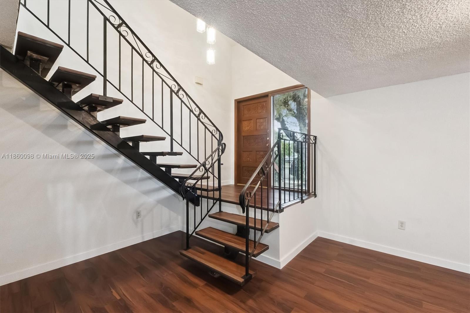 An entryway features a wooden front door, dark wood flooring, and a floating staircase — 5975 SW 137th Ave # 702, Miami FL 33183, MIAMI, FL