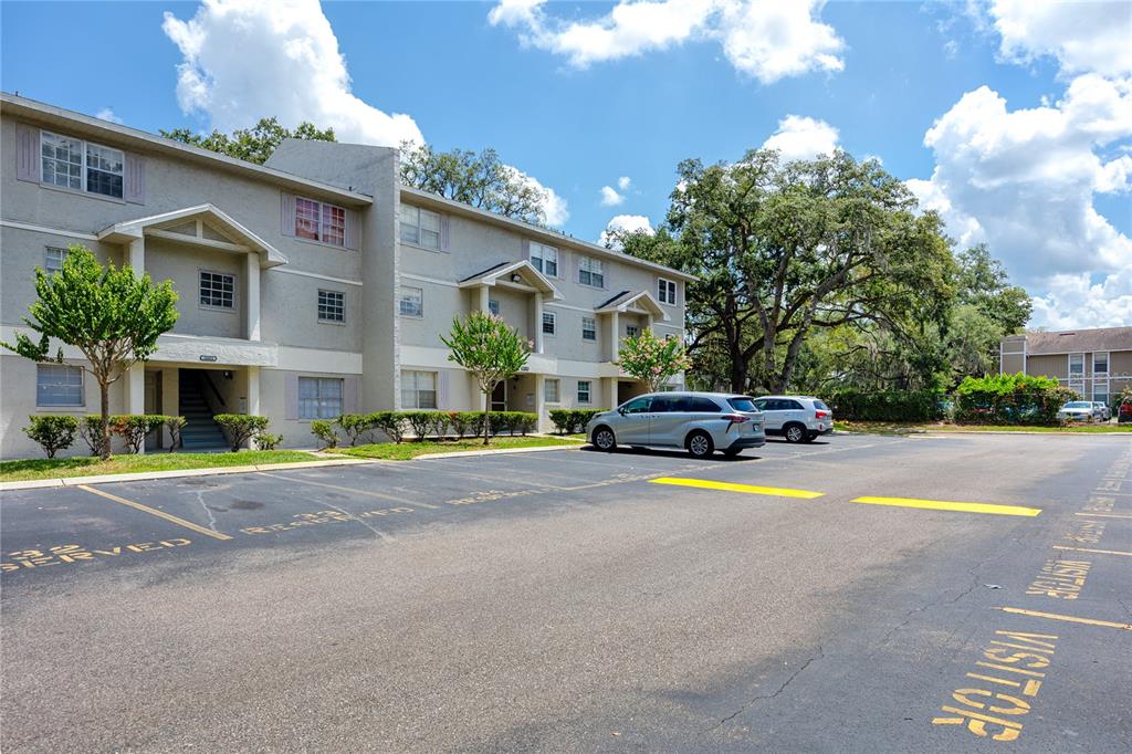A multi-story apartment building with a parking lot in the foreground — 14424 REUTER STRASSE CIRCLE UNIT 104, TAMPA, FL