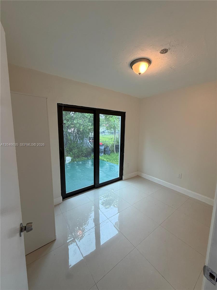 A small room with light-colored tile flooring, a ceiling light, and sliding glass doors — NORTH MIAMI, FL