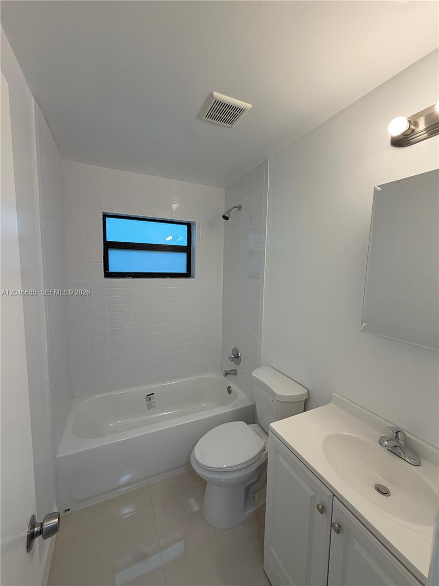 A bathroom features a white bathtub with a showerhead, a toilet, and a vanity sink — NORTH MIAMI, FL