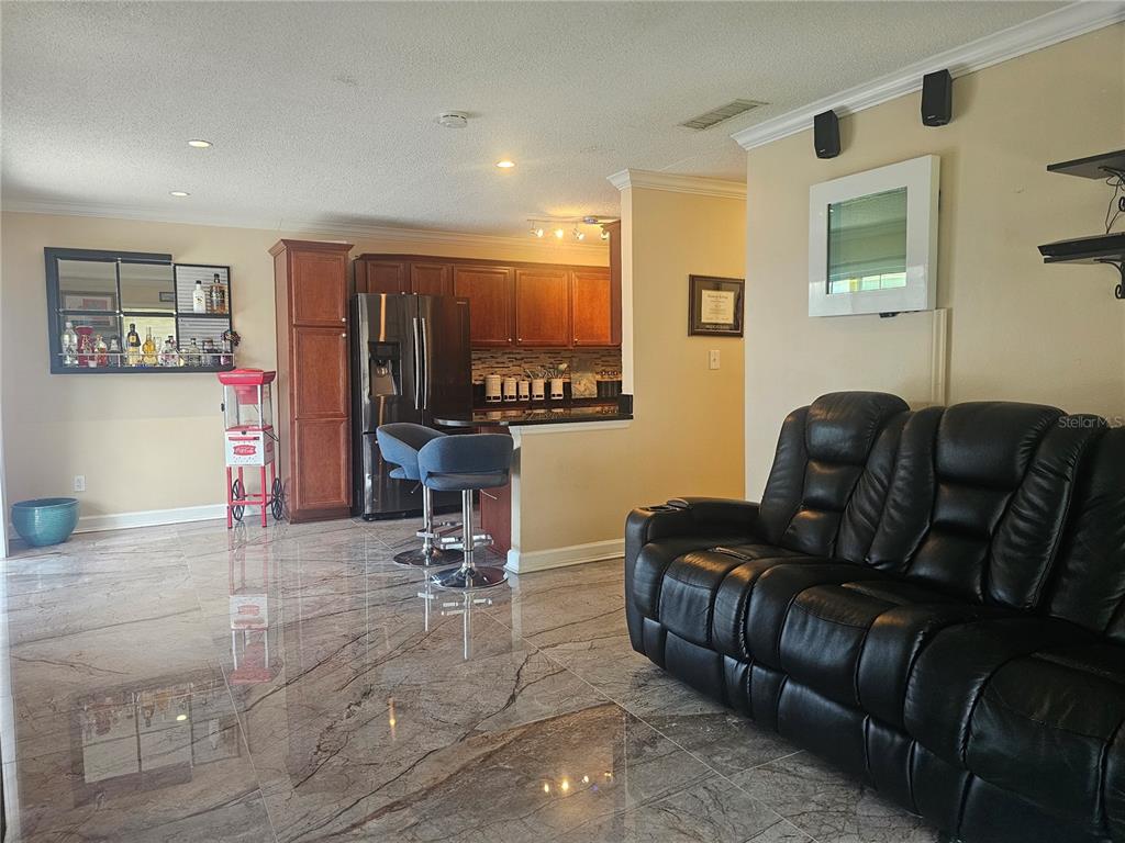 A living room with marble-look tile floors, a black leather sofa, and an open kitchen — 4882 CONWAY ROAD UNIT 82, ORLANDO, FL
