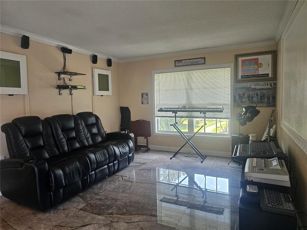 A room with a black leather sofa, a keyboard on a stand, and tiled flooring — 4882 CONWAY ROAD UNIT 82, ORLANDO, FL
