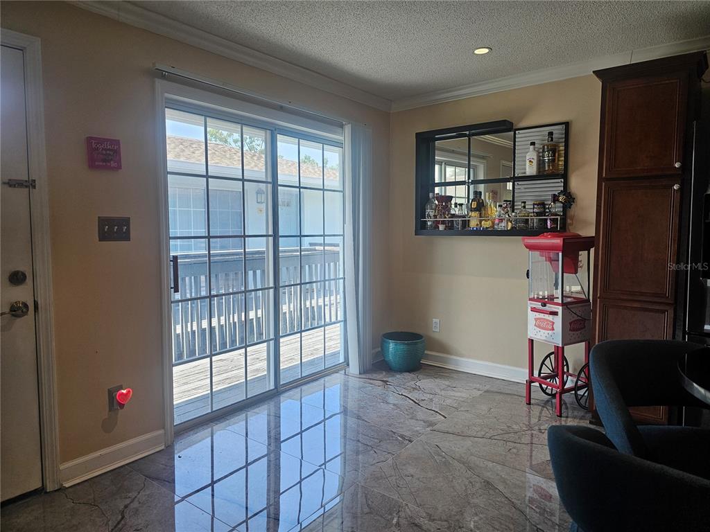 A room with marble-look tile flooring, a sliding glass door, a bar area, and popcorn machine — 4882 CONWAY ROAD UNIT 82, ORLANDO, FL
