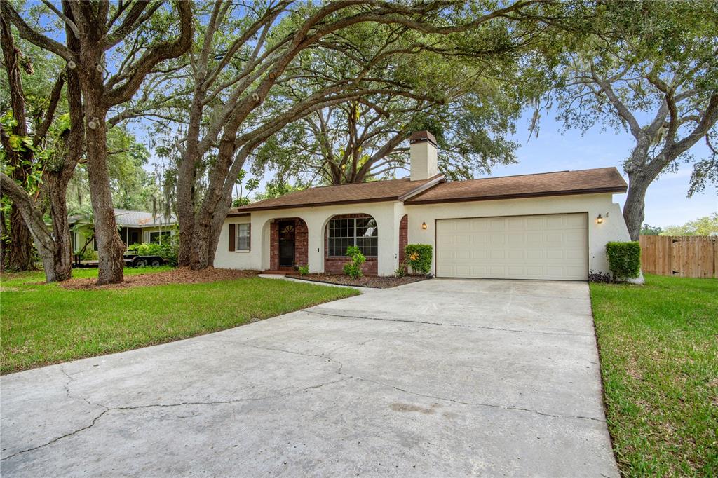 A single-story house with a concrete driveway, brick accents, and large trees in the yard — 2217 BOXWOOD WAY, BRANDON, FL
