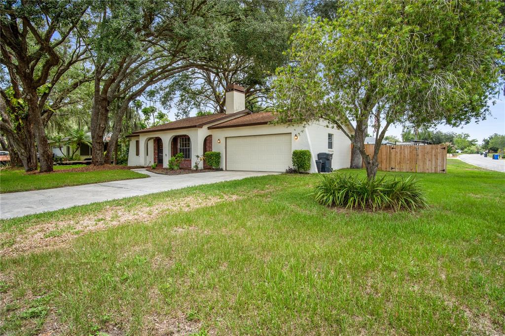 A single-story house with a beige stucco exterior, a two-car garage, and large oak trees — 2217 BOXWOOD WAY, BRANDON, FL