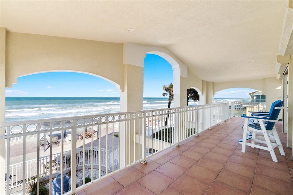 A covered balcony with tile flooring and a white railing overlooks the ocean and beach — 3837-3839 S ATLANTIC AVENUE, DAYTONA BEACH, FL