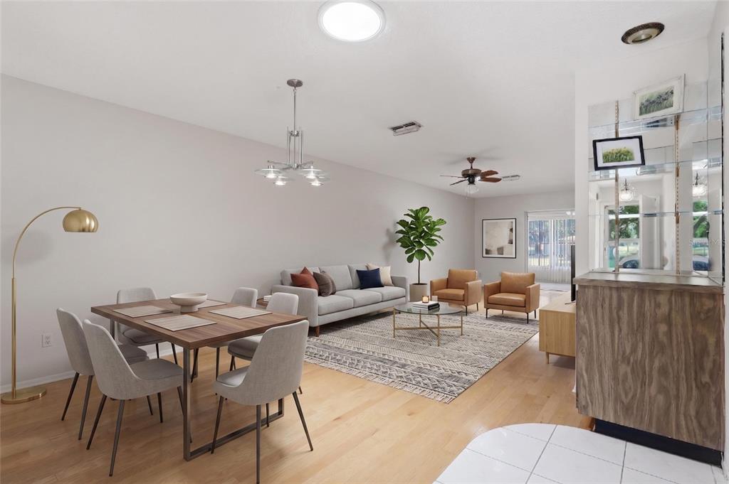 An open-concept living and dining room with light wood floors and neutral furniture — 2211 LARK CIRCLE W UNIT D, PALM HARBOR, FL