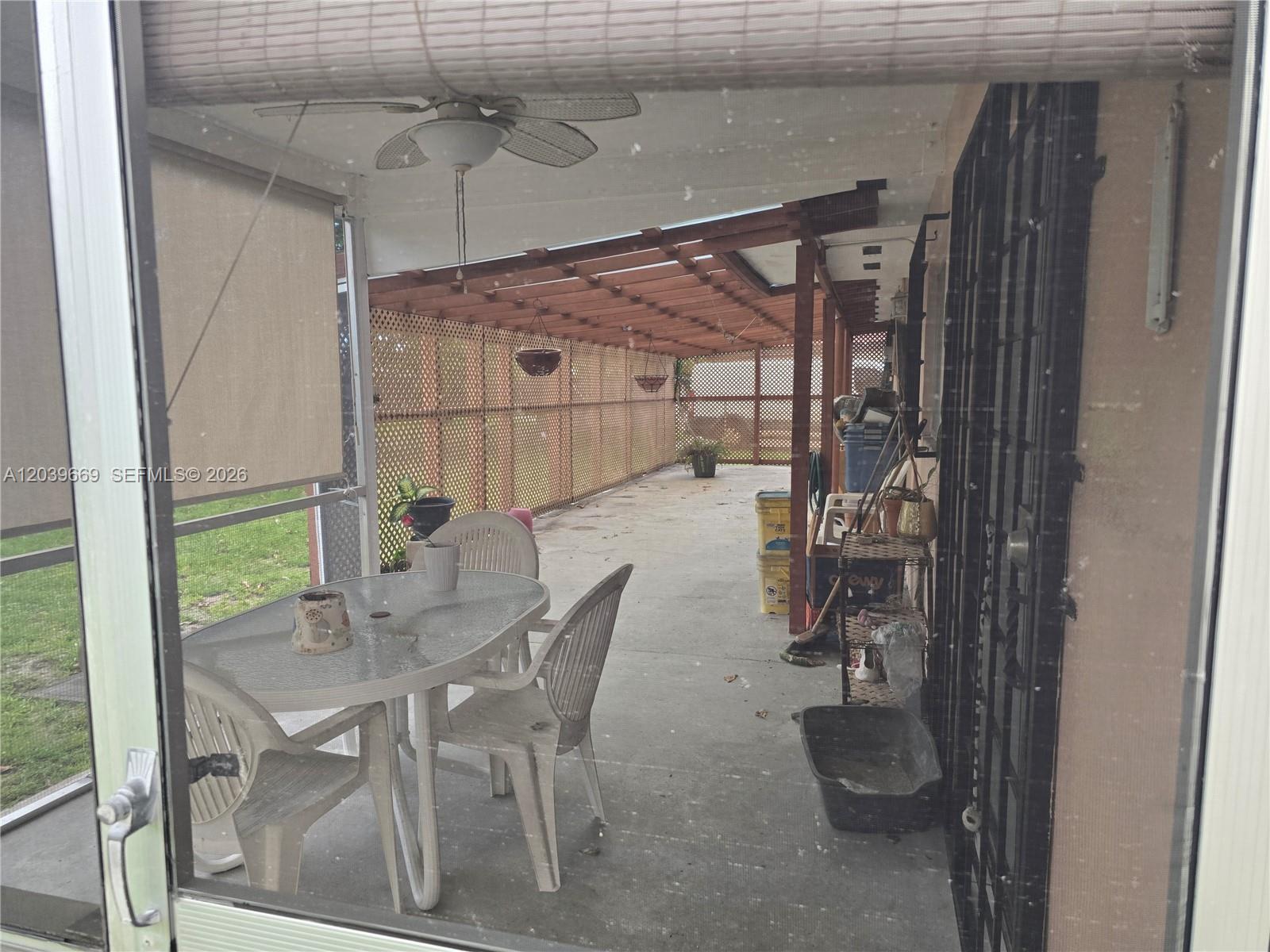 A covered patio features a dining set, a wooden pergola, and a lattice privacy screen — MIAMI GARDENS, FL