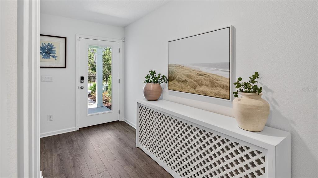 An entryway features a white radiator cover console table, a landscape painting, and a glass-paneled door — 40 MULLIGAN WAY, BUNNELL, FL