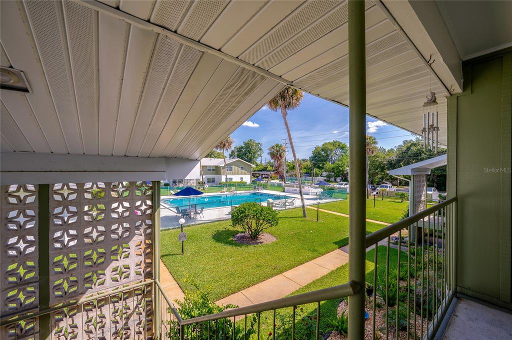 A view from a covered balcony overlooking a community swimming pool and green lawn — 840 CENTER AVENUE UNIT 100, HOLLY HILL, FL