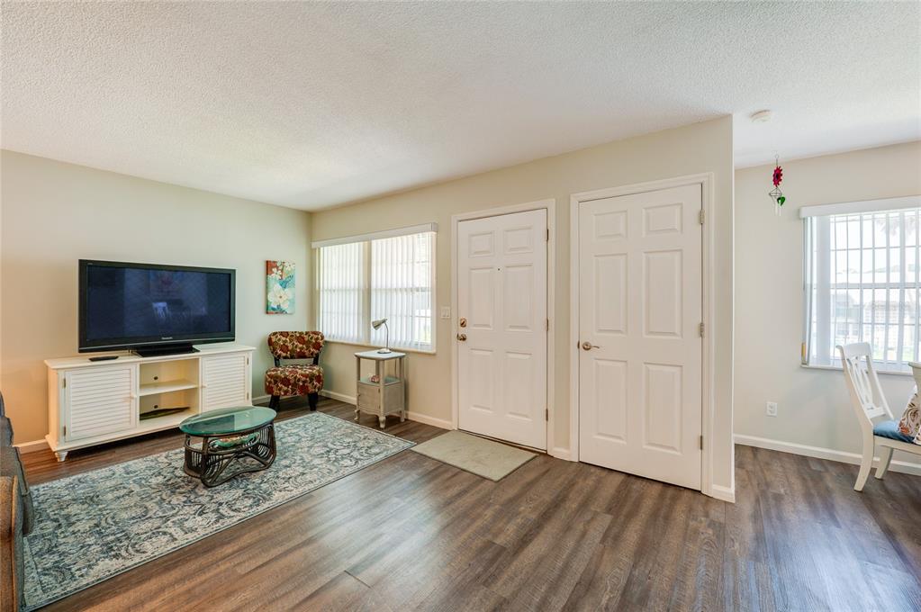 A living room with wood-look flooring, a television console, and two white interior doors — 840 CENTER AVENUE UNIT 100, HOLLY HILL, FL