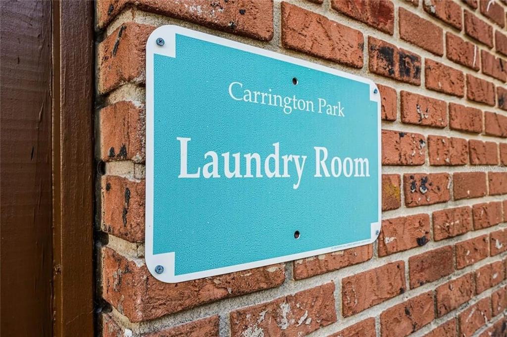 A teal sign labeled Carrington Park Laundry Room is mounted on a red brick wall — 2422 BRANCH WAY UNIT 100, MAITLAND, FL