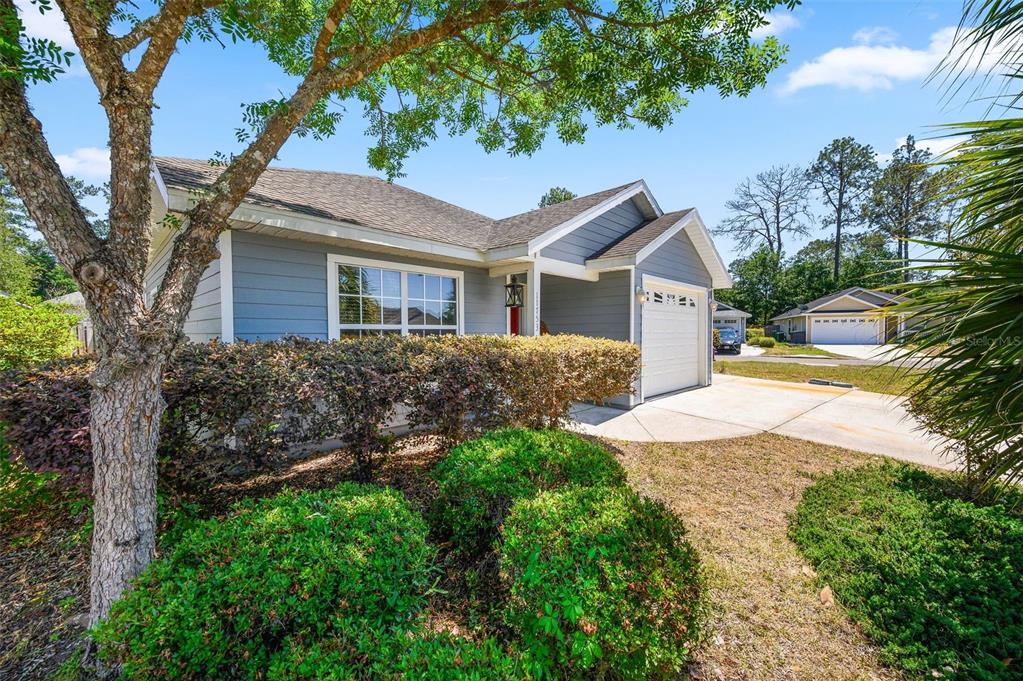 A single-story gray house with a white garage and a landscaped front yard — 11753 NW 60TH TERRACE, ALACHUA, FL