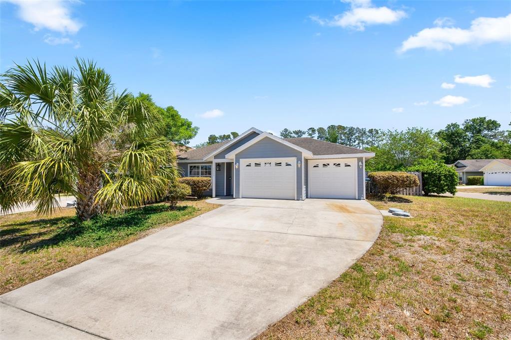 A single-story house with a two-car garage, concrete driveway, and a palm tree in front — 11753 NW 60TH TERRACE, ALACHUA, FL