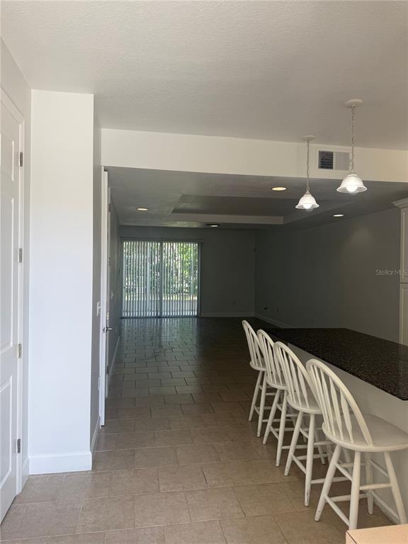 A long, open-concept living area with tile flooring leads to a kitchen with white cabinets — 2053 GREEN OAK COURT, KISSIMMEE, FL
