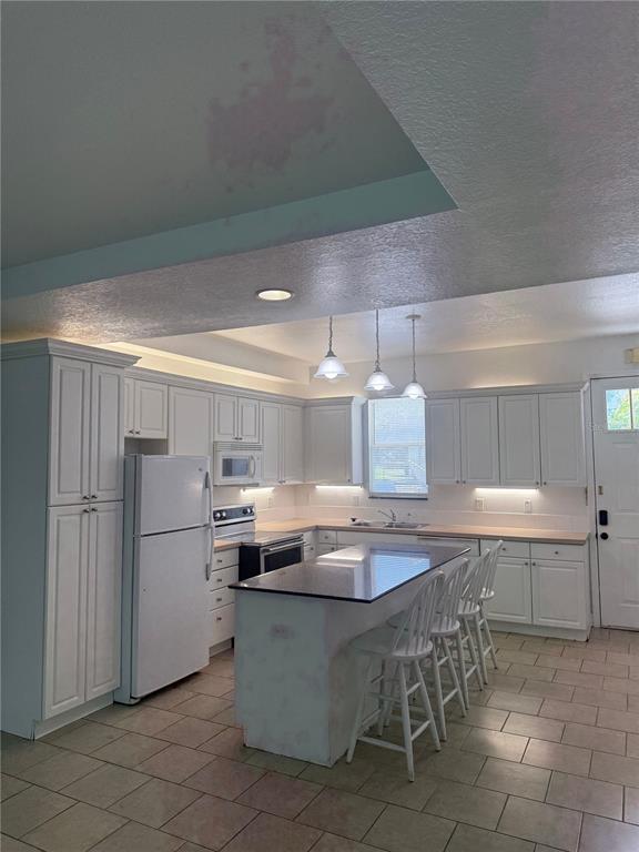 An open-concept living area with tile flooring leads into a white kitchen with an island — 2053 GREEN OAK COURT, KISSIMMEE, FL