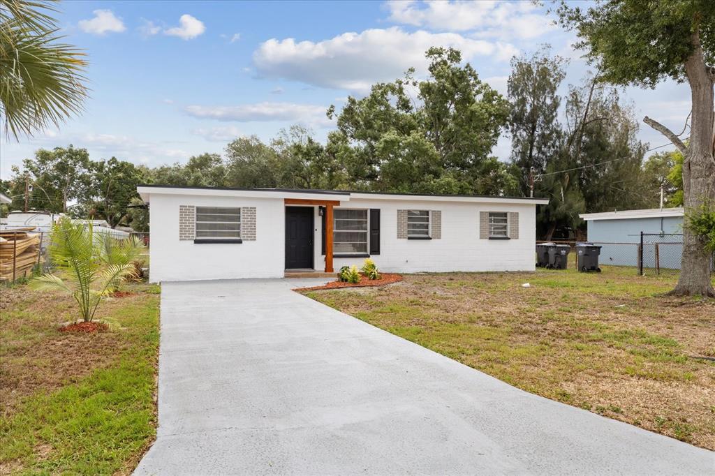 A white, single-story house with a concrete driveway and a dark front door — 4922 S 82ND STREET, TAMPA, FL