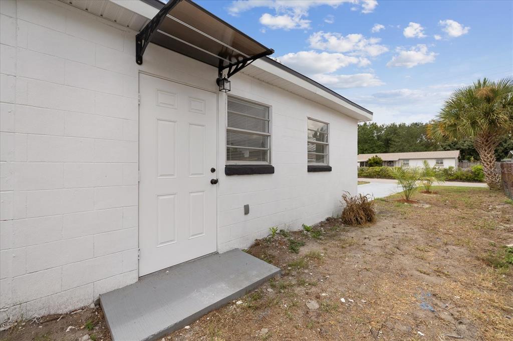 A white concrete block building features a white door with a small awning and windows — 4922 S 82ND STREET, TAMPA, FL