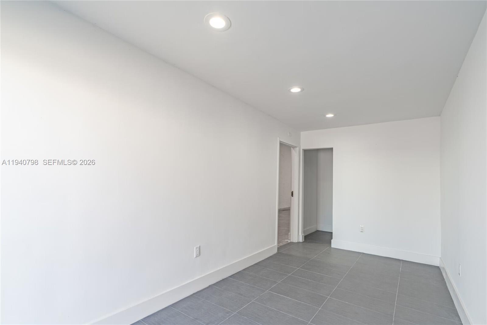 A minimalist room features white walls, recessed ceiling lights, and grey tiled flooring — 1670 W 31st Pl, Hialeah FL 33012, HIALEAH, FL